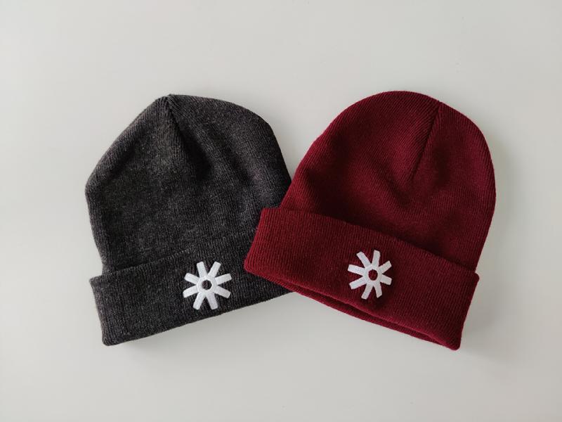 A gray beanie with a white star that has eight points and a red beanie with a white star that has eight points